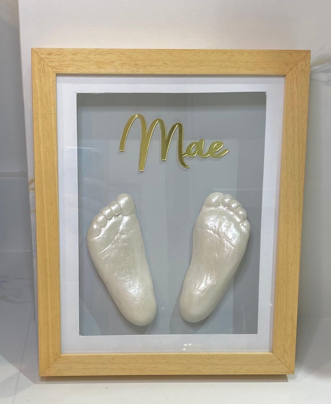 Pearl-finished baby feet cast in a hardwood frame