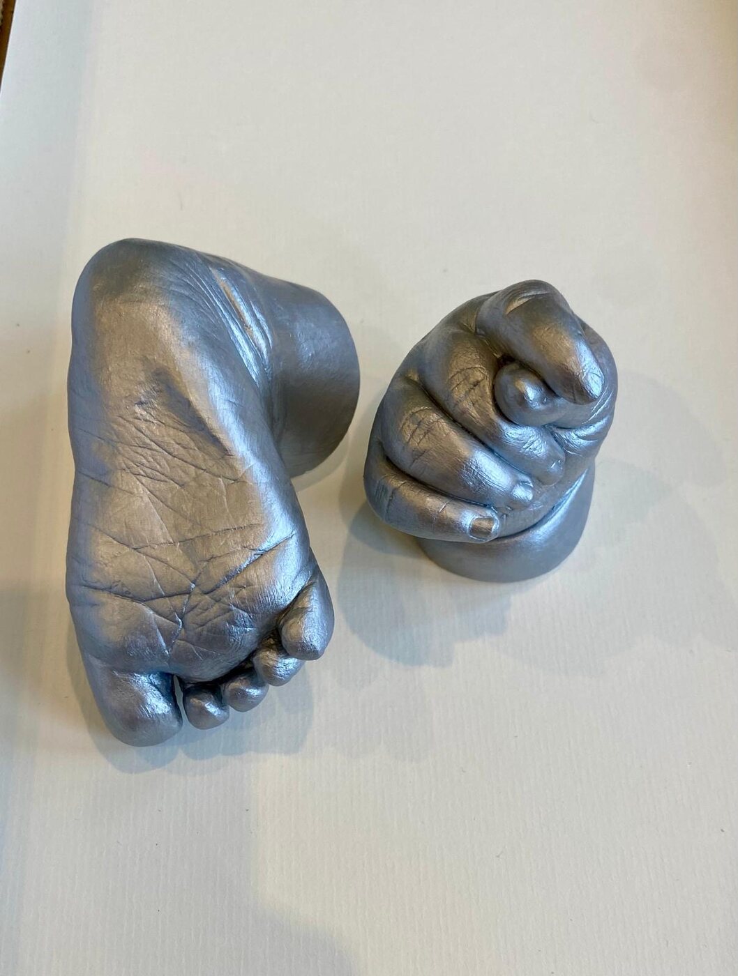 Silver cast of a baby foot and clenched hand